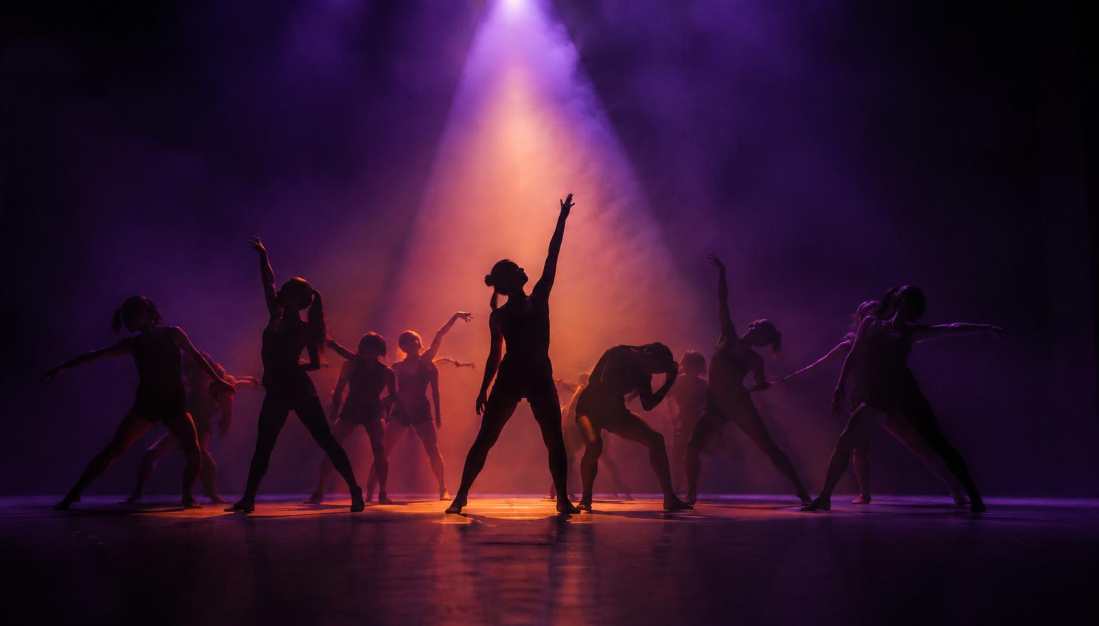 Illustrative image: dancers in silhouette under a stage spotlight